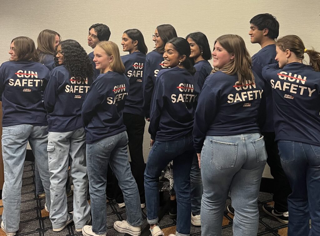 Youth Council group photo with their backs to the camera showing "Gun Safety" on the backs of their shirts